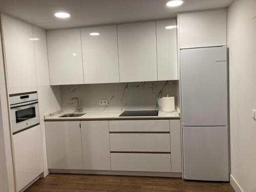 a kitchen with white cabinets and a refrigerator at El Escondite De La Catedral Vivienda De Uso Turistico VUT 09-612 in Burgos