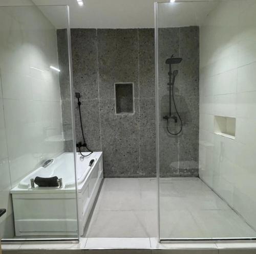 a bathroom with a shower and a tub and a sink at House 12 Two-Bed Studio Apartment in Ilorin