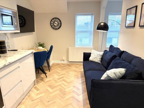 a living room with a blue couch and a kitchen at The Loft Apartments Cardiff Central in Cardiff