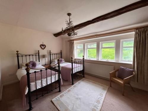 ein Schlafzimmer mit zwei Betten, einem Stuhl und einem Fenster in der Unterkunft Royds Hall Cottage in Keighley