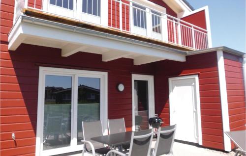 a red house with a balcony and a table and chairs at Awesome Home In Dagebüll With Sauna in Dagebüll
