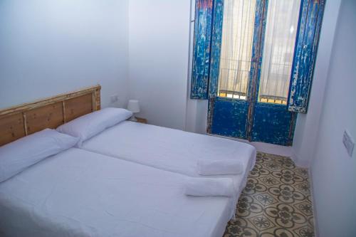 a small bedroom with a white bed and two windows at Pigal in Tarragona