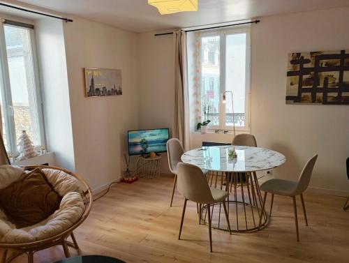 a living room with a table and chairs and a television at L 'Échappée Marine au coeur de Concarneau in Concarneau