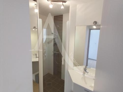 une salle de bain blanche avec un lavabo et un miroir dans l'établissement 6 PERS, 2 CHAMBRES, DERNIER ETAGE EN FRONT DE MER, à Sète