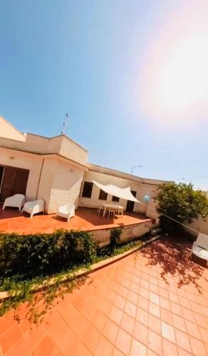 een patio met witte stoelen en een gebouw bij Farfalla in San Vito lo Capo