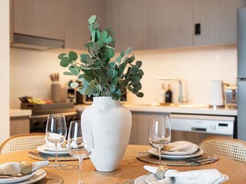 a table with a white vase with a plant in it at The Chic Downtown Suite Luxury near Burj Khalifa in Dubai