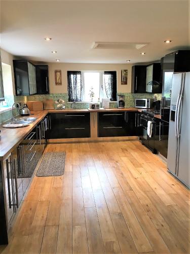 a large kitchen with a wooden floor and a refrigerator at Country House Ashdene in Highworth