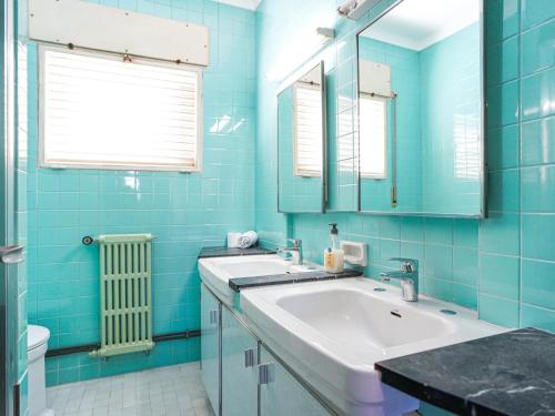 Baño azul con 2 lavabos y espejo en Bed BCN Hills House, en Barcelona