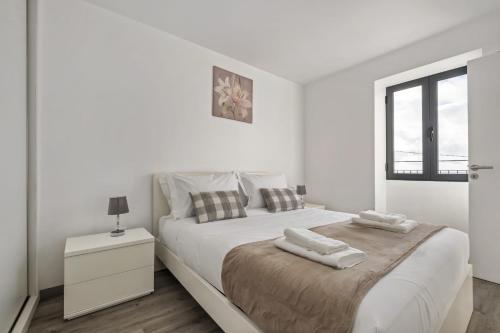 a white bedroom with a large bed and a window at Seaside Charm II in Câmara de Lobos