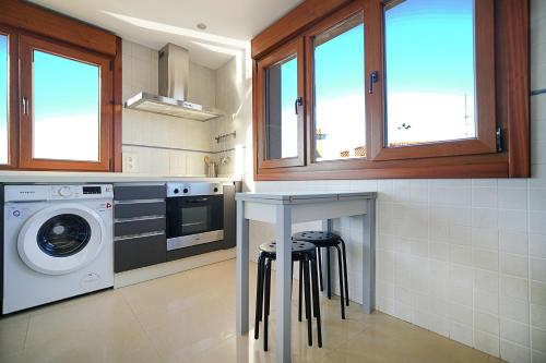 kuchnia z pralką i stołem z krzesłami w obiekcie Apartamento con terraza con vistas al mar w mieście Villanueva de Arosa