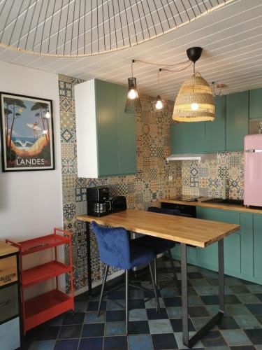 une cuisine avec des placards verts et une table en bois dans l'établissement Capbreton plage centrale Vue Mer Appart Parking, à Capbreton
