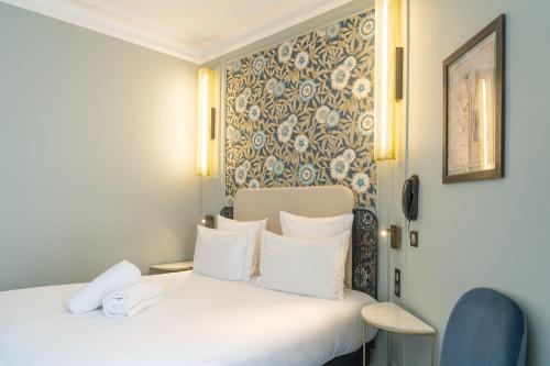 a hotel room with two beds and a chair at ELSA, Hôtel Paris in Paris