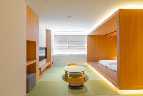 a bedroom with a bed and a table and chairs at Torifito Hotel & Pod Kanazawa in Kanazawa