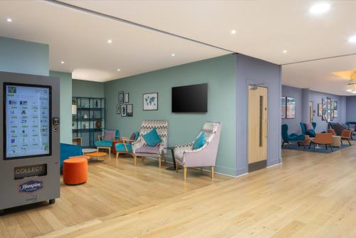 a waiting room with chairs and a flat screen tv at Hampton by Hilton London Gatwick Airport in Horley