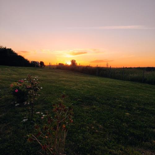 a field of grass with a sunset in the background at Jolie longère près Canal Nantes-Brest ' Pétanque in Guenrouet