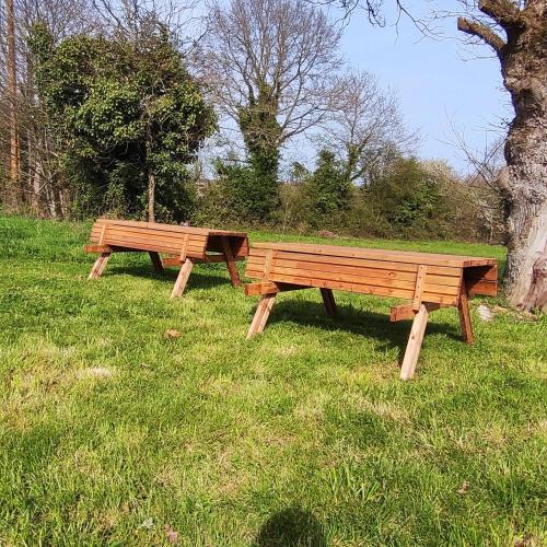 two wooden benches sitting in the grass in a field at Jolie longère près Canal Nantes-Brest ' Pétanque in Guenrouet