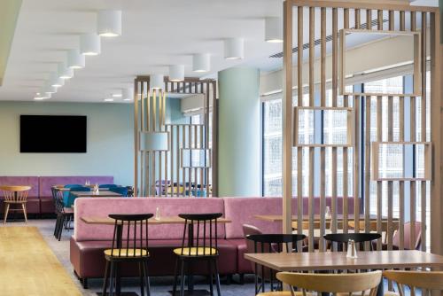 a restaurant with a pink couch and tables and chairs at Hampton by Hilton London Gatwick Airport in Horley