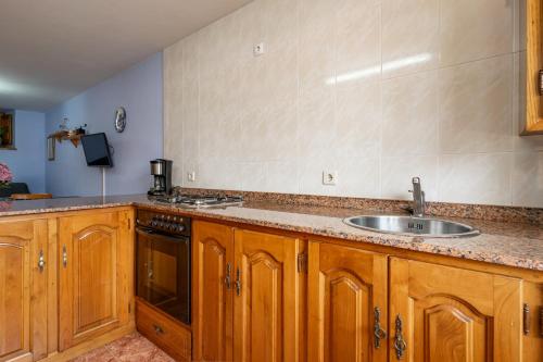 a kitchen with wooden cabinets and a sink at Vidª Vac Honorato 2 in Santa Eulalia
