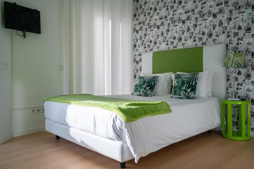a bedroom with a white bed with a green headboard at By the Sea - Nazaré in Nazaré