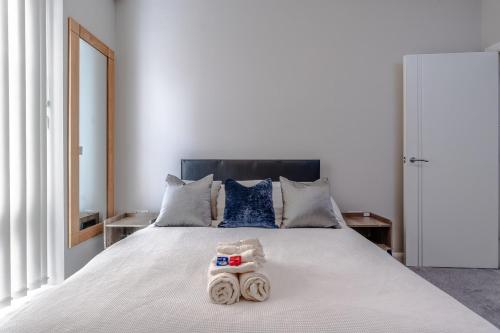 a bedroom with a white bed with towels on it at Garden View Serviced Flat by Castle Park, Lift in Bristol