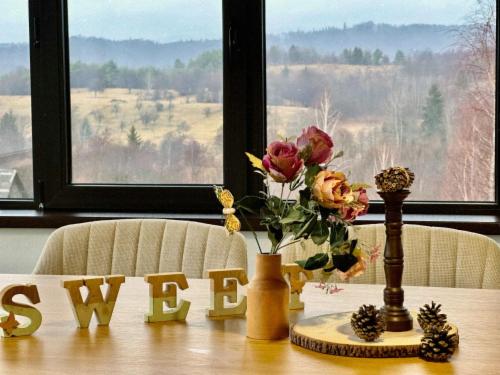 a table with a vase of flowers and a view at Pensiunea Grădina Ascunsa in Bughea de Jos