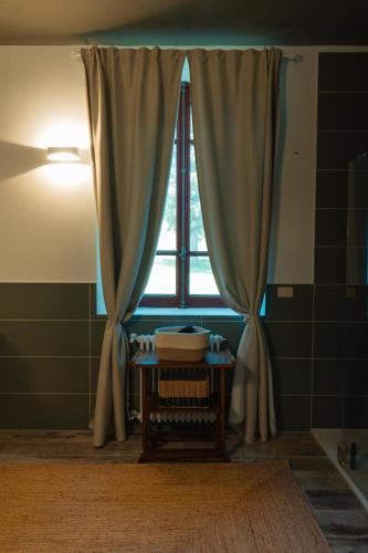a bathroom with a window with curtains and a table at Origine Country Farm in Tabiano