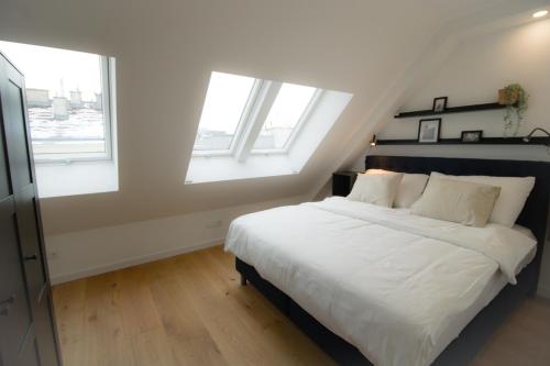 a bedroom with a bed with white sheets and two windows at Smart Luxury Apartment in Vienna l JOS25 in Vienna