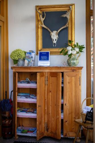 a wooden cabinet with a picture of a deer skull on the wall at Villa Marienhof in Annenheim