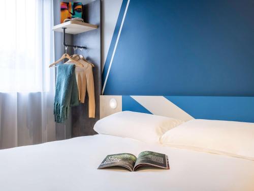 a book laying on top of a bed at ibis budget Arlon Porte du Luxembourg in Arlon