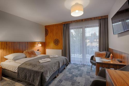 a bedroom with a bed and a desk and a window at Willa Marti GOLD in Zakopane