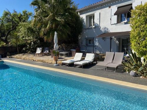 une piscine avec des chaises longues et une maison dans l'établissement NOUVEAU ! VILLA LORANA Entre mer et Vignes, à Saint-Cyr-sur-Mer