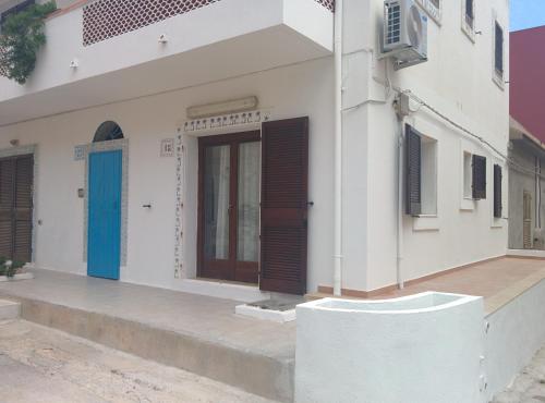 a white building with a blue door and windows at Doria 18 in Lampedusa