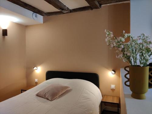 a bedroom with a bed with a vase of flowers at Cœur de Chinon, tout confort ! in Chinon