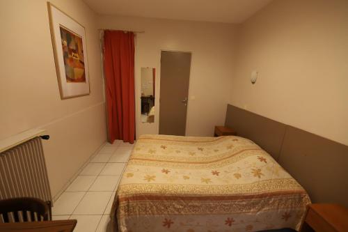 a small bedroom with a bed and a red curtain at Hôtel du Roussillon in Paris