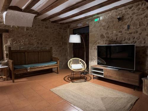 a living room with a flat screen tv and a chair at El Molí Nou - Rural flats in Peñarroya de Tastavins