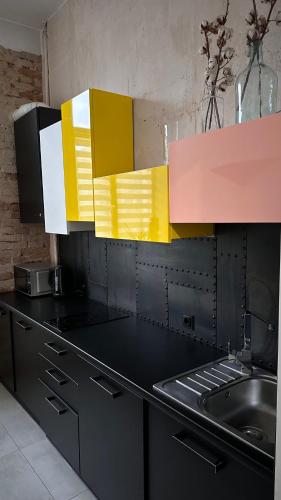 a kitchen with black and yellow cabinets and a sink at Smolynja stail in Ternopilʼ