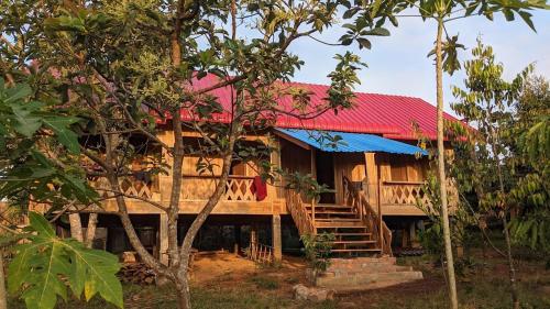 a wooden house with a red roof and stairs at Cardamom Community Center in Moăt Preăh