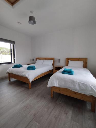 two beds sitting in a room with a window at Craggy Cottage 1 in Inishturk