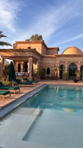 a house with a swimming pool in front of a building at Villa d architecte Marrakech in Oulad Jellal