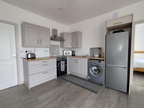 a kitchen with a refrigerator and a washing machine at Craggy Cottage 1 in Inishturk