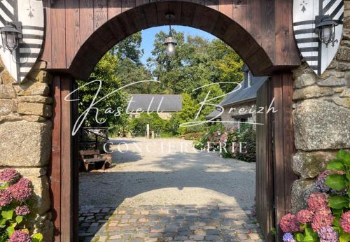 an archway entrance to a garden with a sign at La familiale du manoir de Kerollivier in Saint-Gilles-Pligeaux