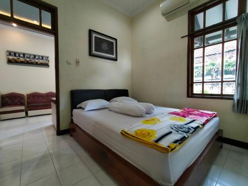 a bedroom with a bed with white sheets and a window at Abadi Homestay in Yogyakarta