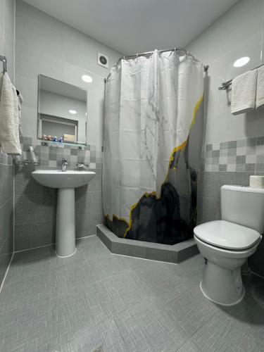 a bathroom with a toilet and a sink and a shower at South Hotel Tashkent in Tashkent
