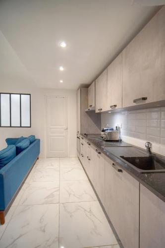 a kitchen with white cabinets and a blue couch at FRGK "Les Jardins de l'Eden" in Le Cannet