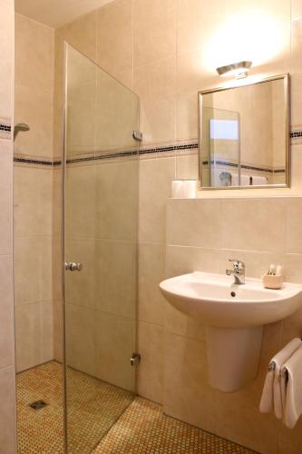 a bathroom with a sink and a shower with a mirror at Hotel Centro in Schwabach