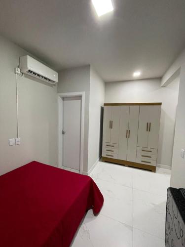 a bedroom with a red bed and cabinets in it at Seu Lar Temporário in Penha