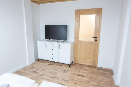 a room with a television on a dresser with a door at Penzion Bistár in Habovka