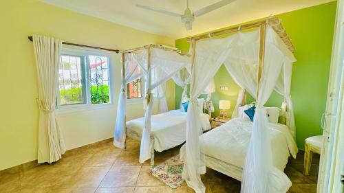 two beds in a bedroom with green walls at Bamburi Beach Villa in Mombasa