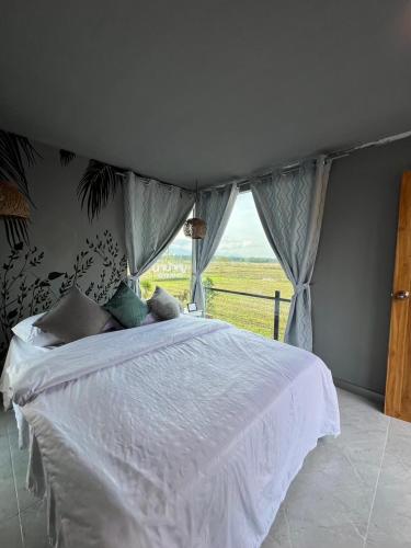 a bedroom with a white bed with a window at นาน้าหมูฟาร์มสเตย์ NanamooFarmStay in Trang