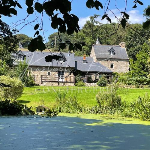 a large stone house on a lush green field at Le Cocon du manoir de Kerollivier in Saint-Gilles-Pligeaux